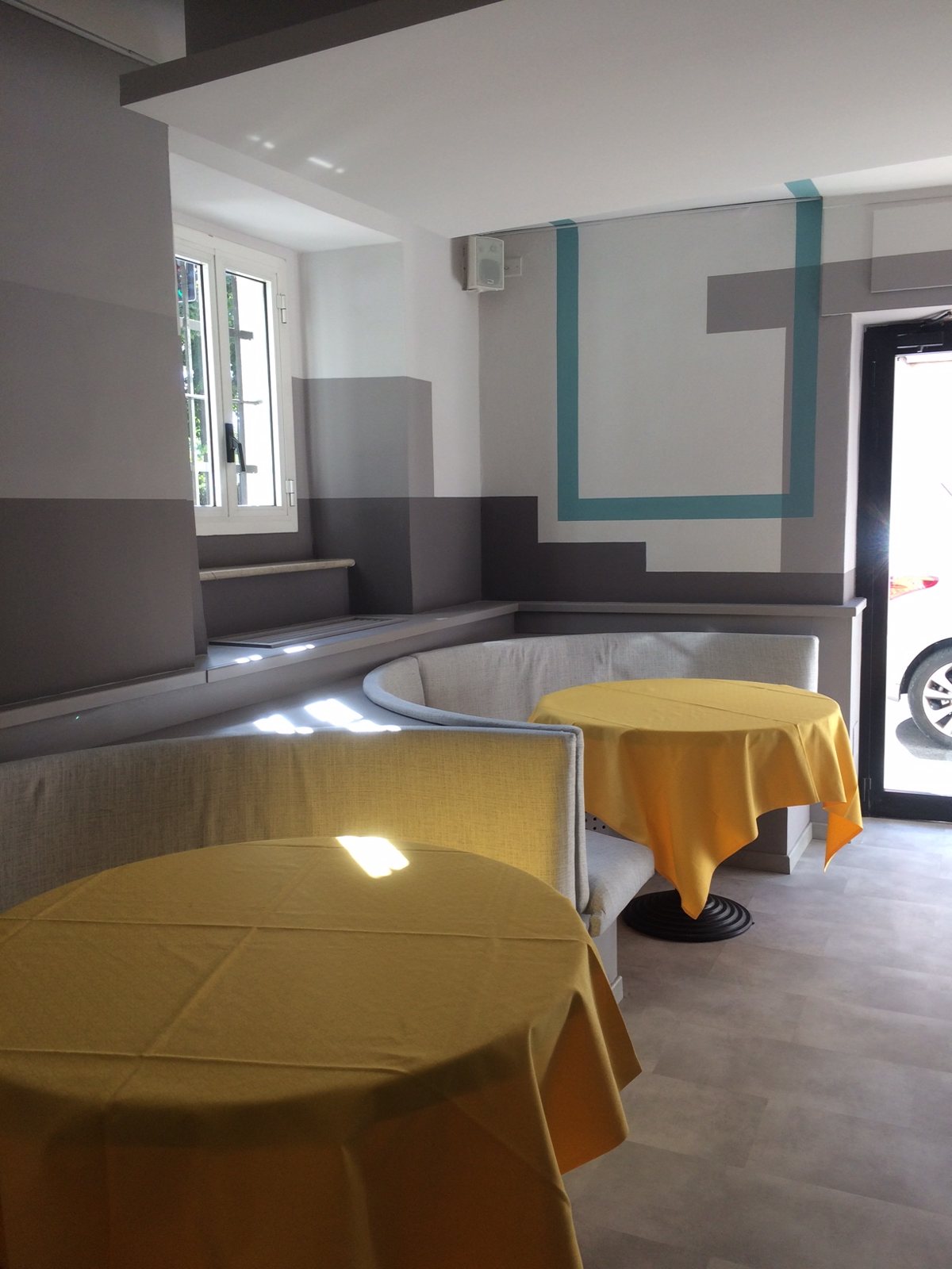 La sala in cantiere: pareti grigie e cornici verde acqua tracciate attorno alle aperture