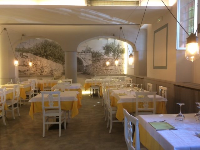 La sala finita e apparecchiata, con le tovaglie gialle sotto gli archi in pietra
