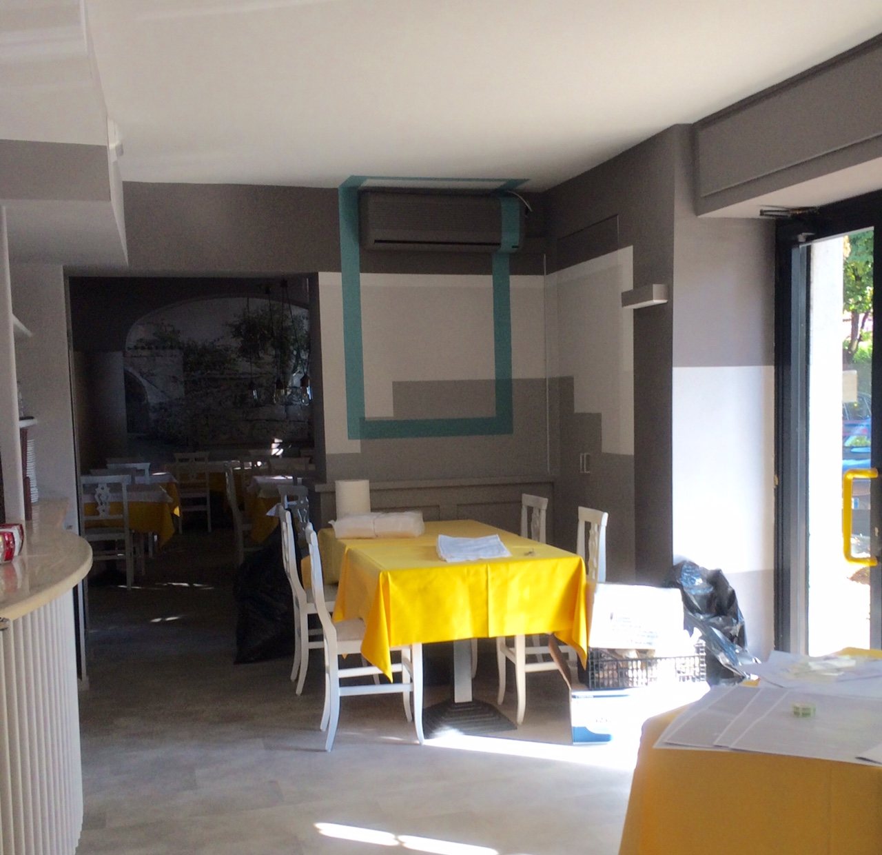 La sala in lavorazione vista verso l'ingresso, con i primi tavoli vestiti di giallo