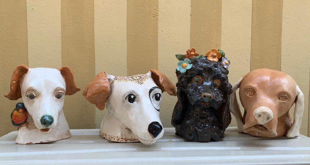 Quattro teste di cane in ceramica allineate davanti alla facciata gialla a strisce
