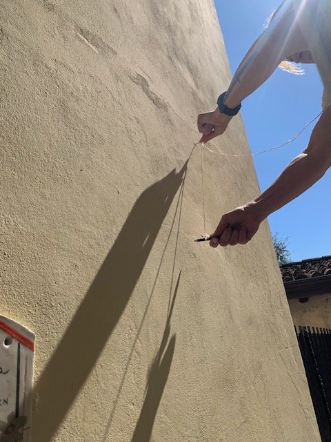 Due mani tendono un filo sulla facciata per tracciare l'arco di una spirale
