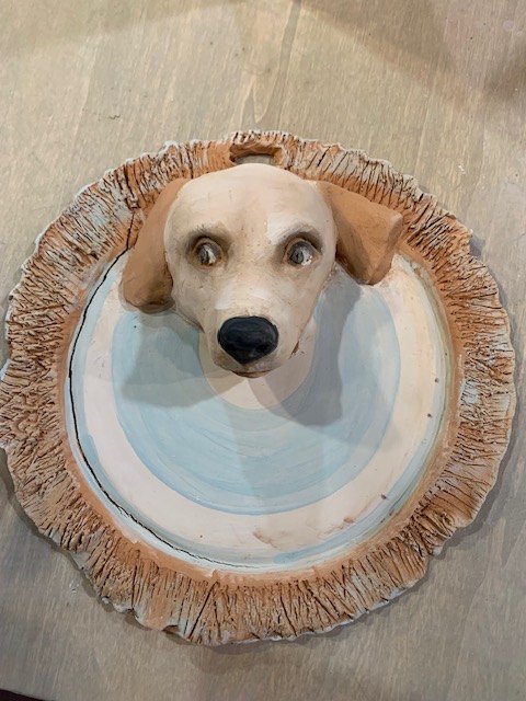 Placca in ceramica smaltata con una testa di cane in rilievo