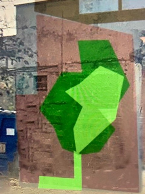Studio di un albero stilizzato verde su un muro di mattoni rossi